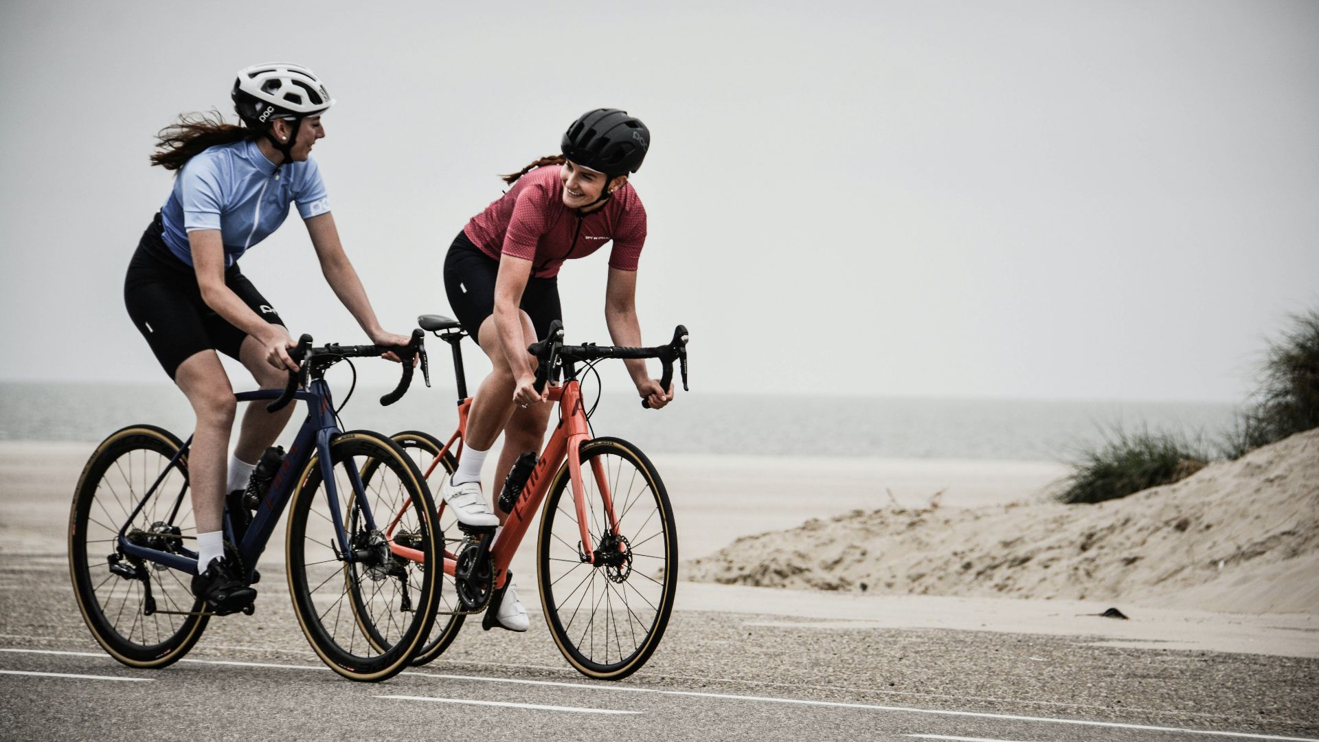 man and woman riding road bikes at the road near shore