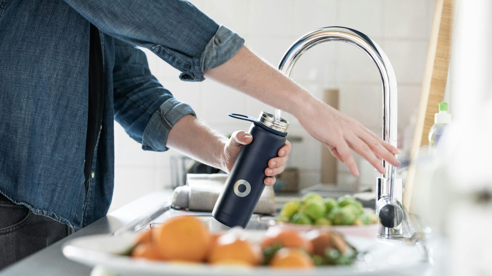 person in blue denim jacket holding stainless steel bottle