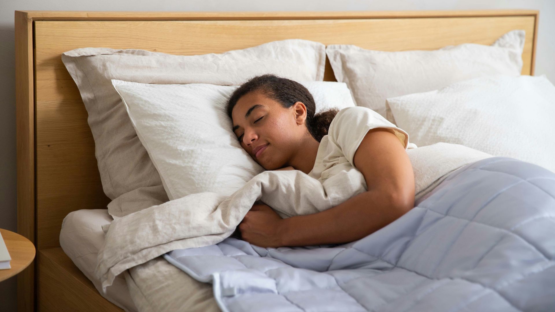 a young girl sleeping in a bed with white sheets