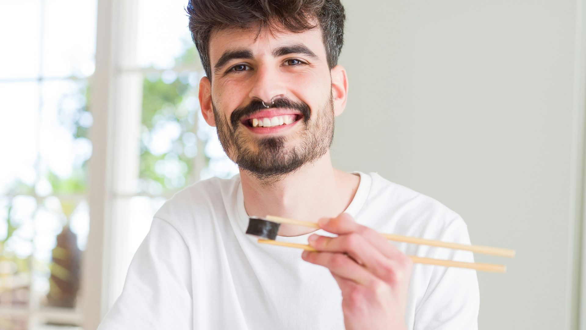 man in white crew neck t-shirt holding white chopsticks