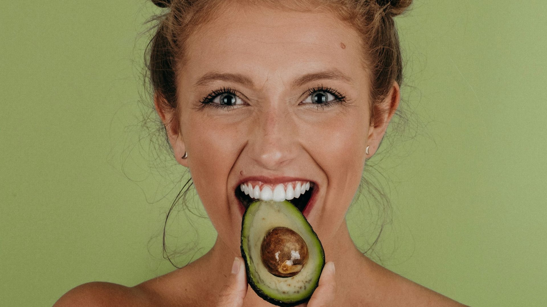 woman holding sliced avocado