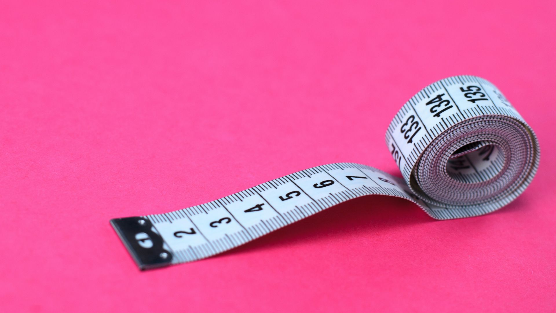 a measuring tape on a pink background