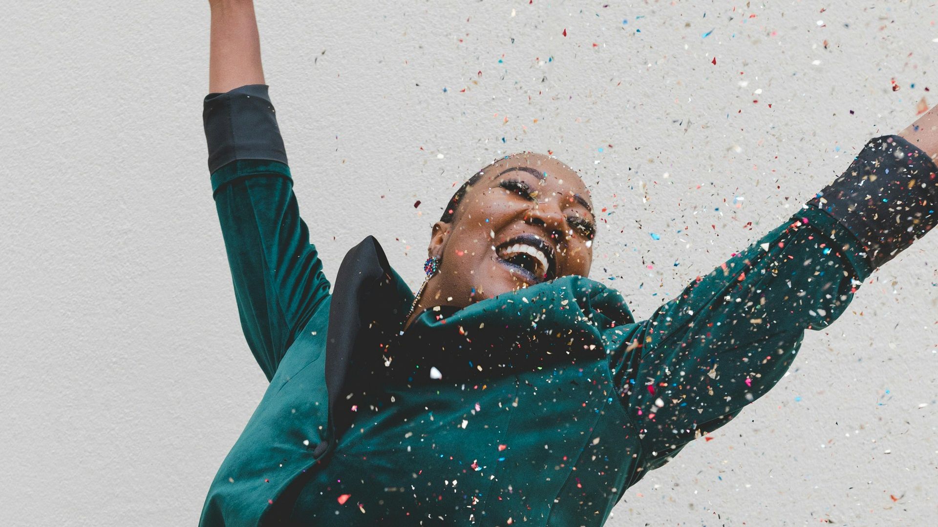 woman in green jacket raising her hands