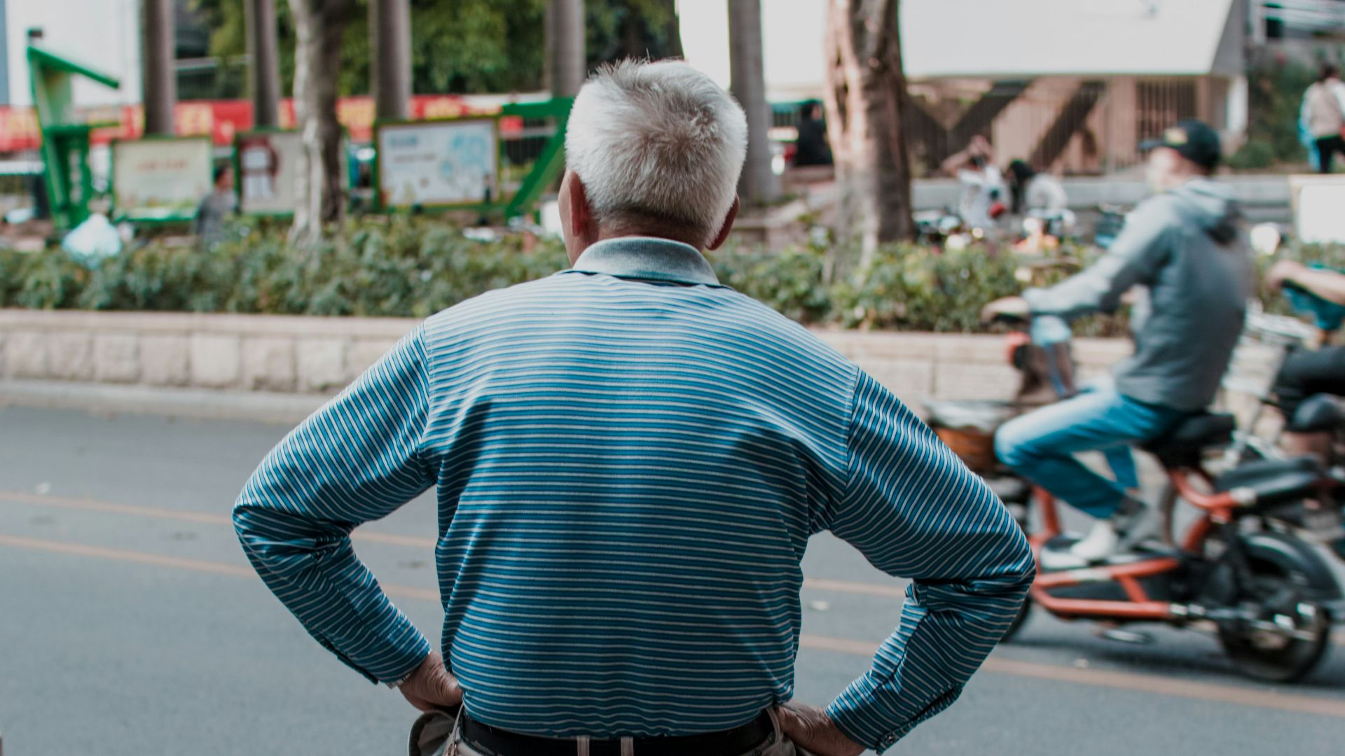 man in blue dress shirt and blue denim jeans standing on road during daytime
