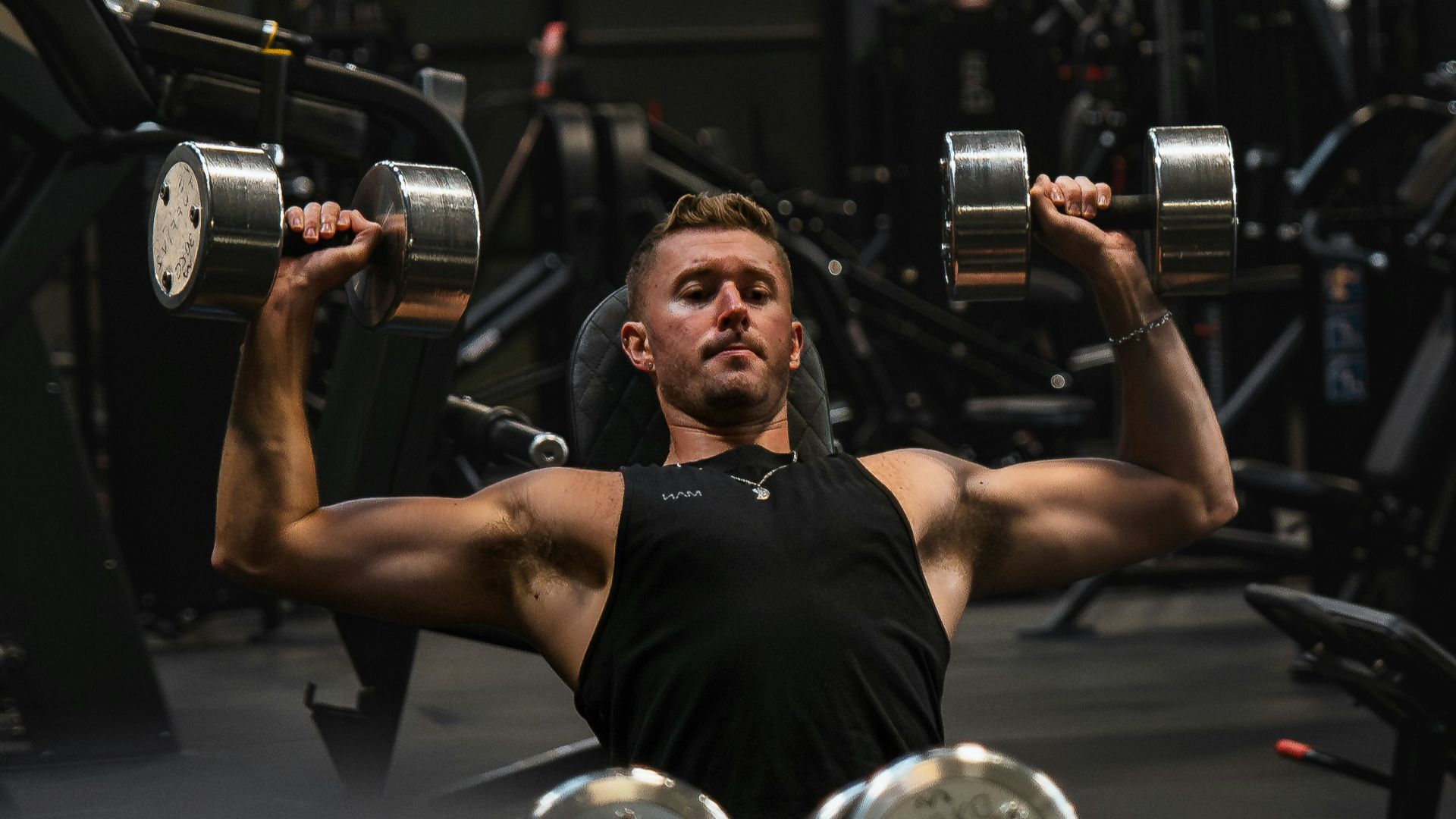 a man in a gym lifting a pair of dumbbells