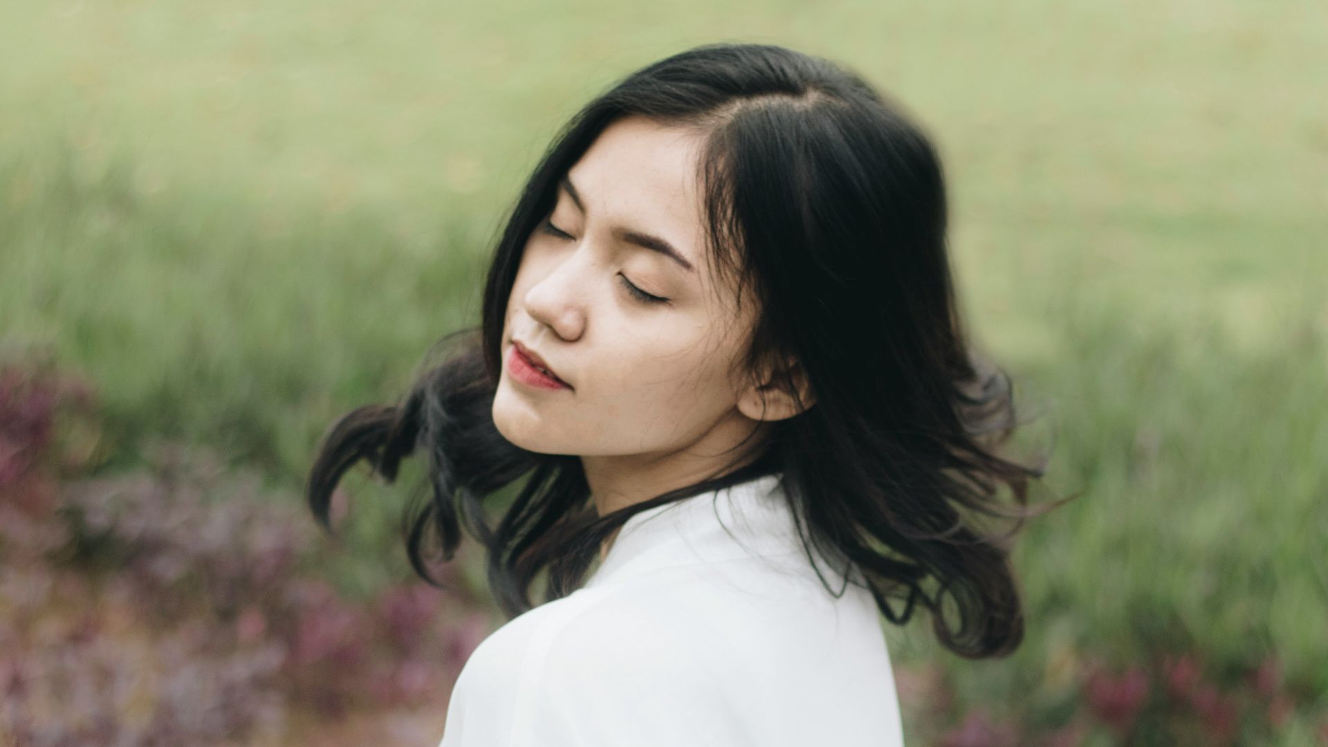 a woman standing in a field with her eyes closed