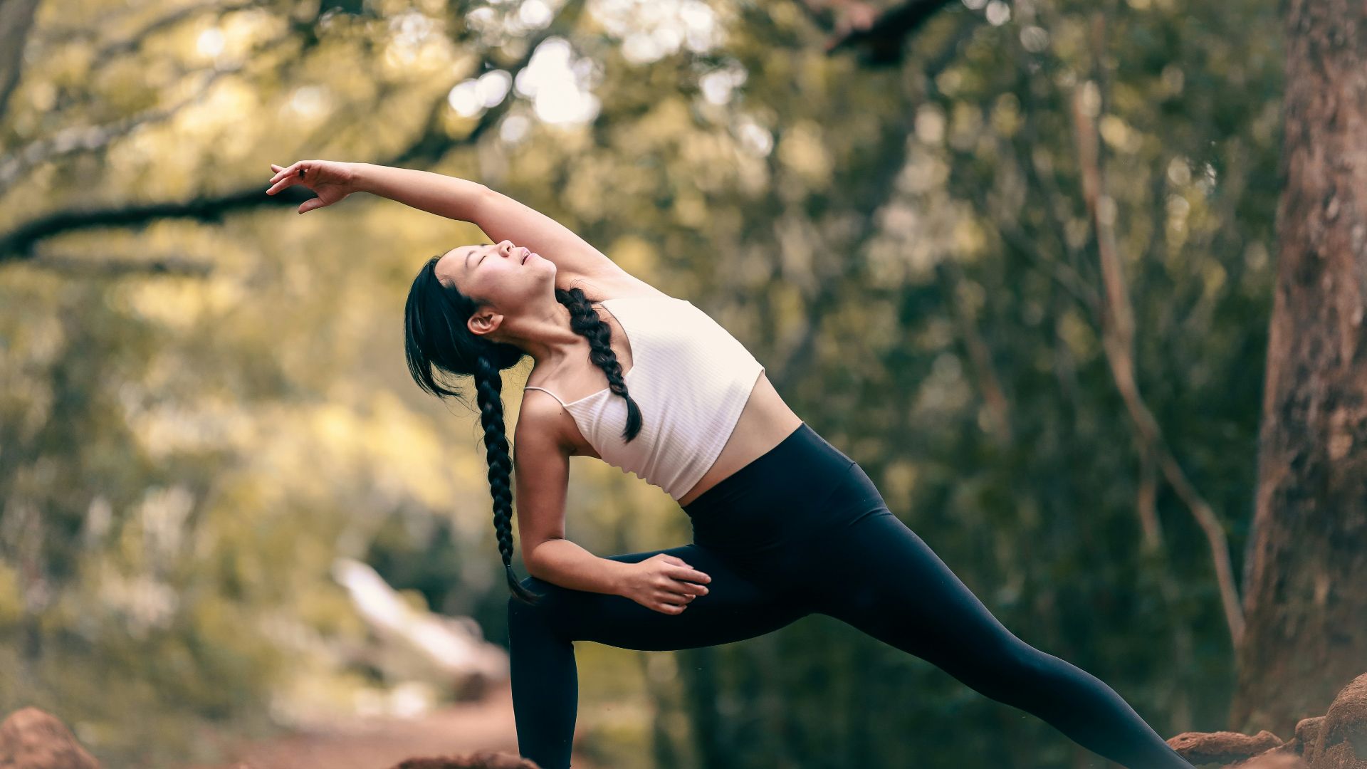 woman in white tank top and black leggings doing yoga during daytime