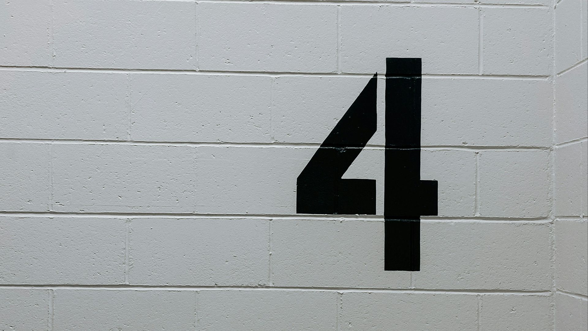 black arrow sign on white brick wall