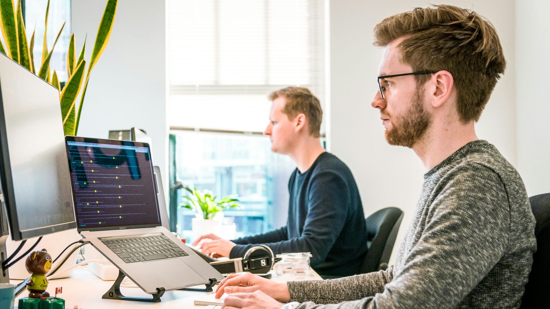 man sitting on chair wearing gray crew-neck long-sleeved shirt using Apple Magic Keyboard