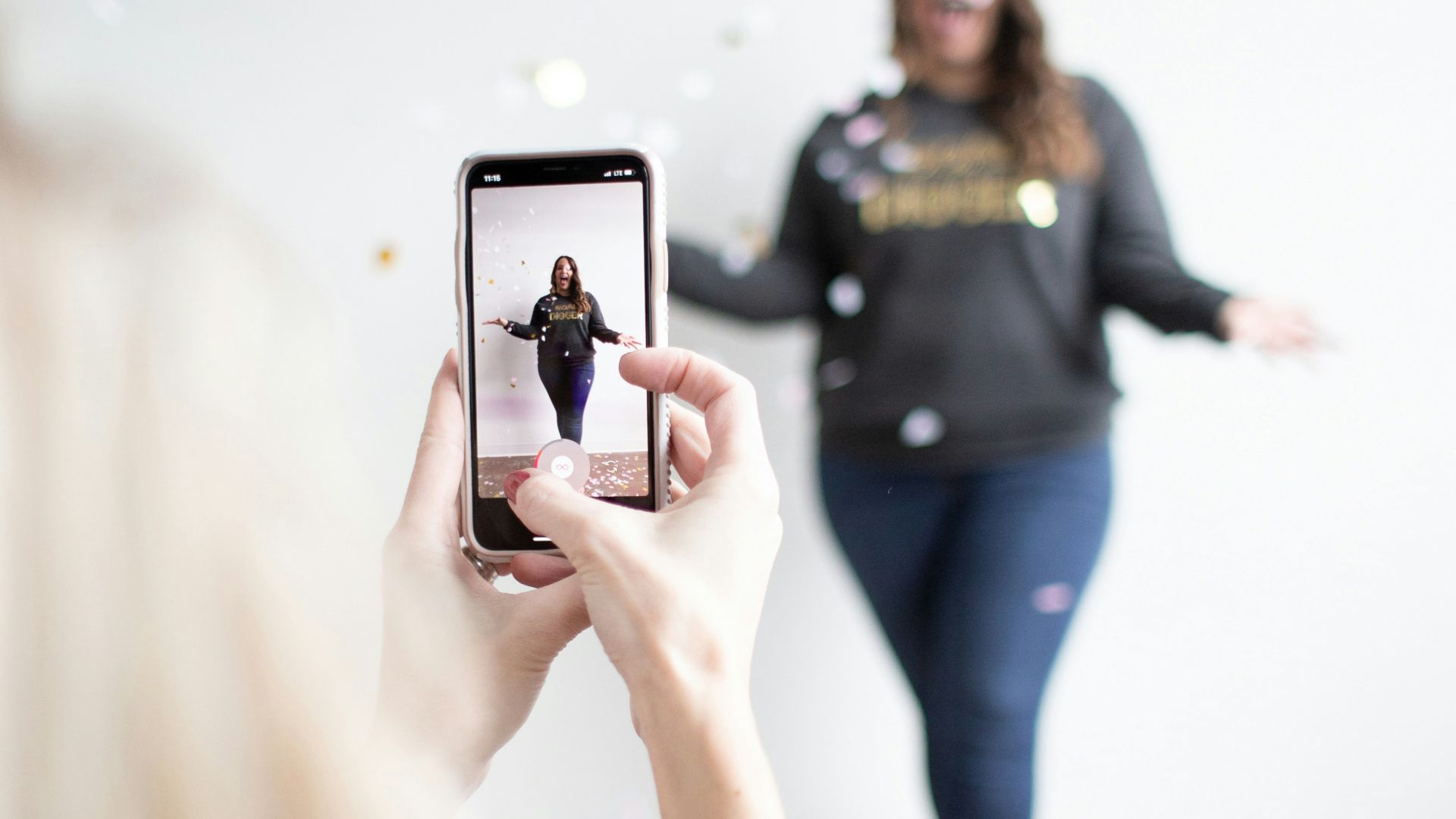 person holding white smartphone taking photo of woman wearing blue jeans
