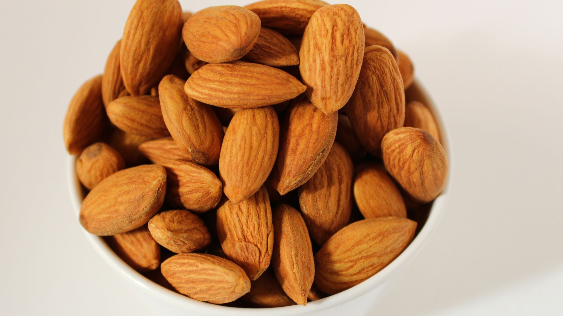 brown almond nuts on white ceramic bowl