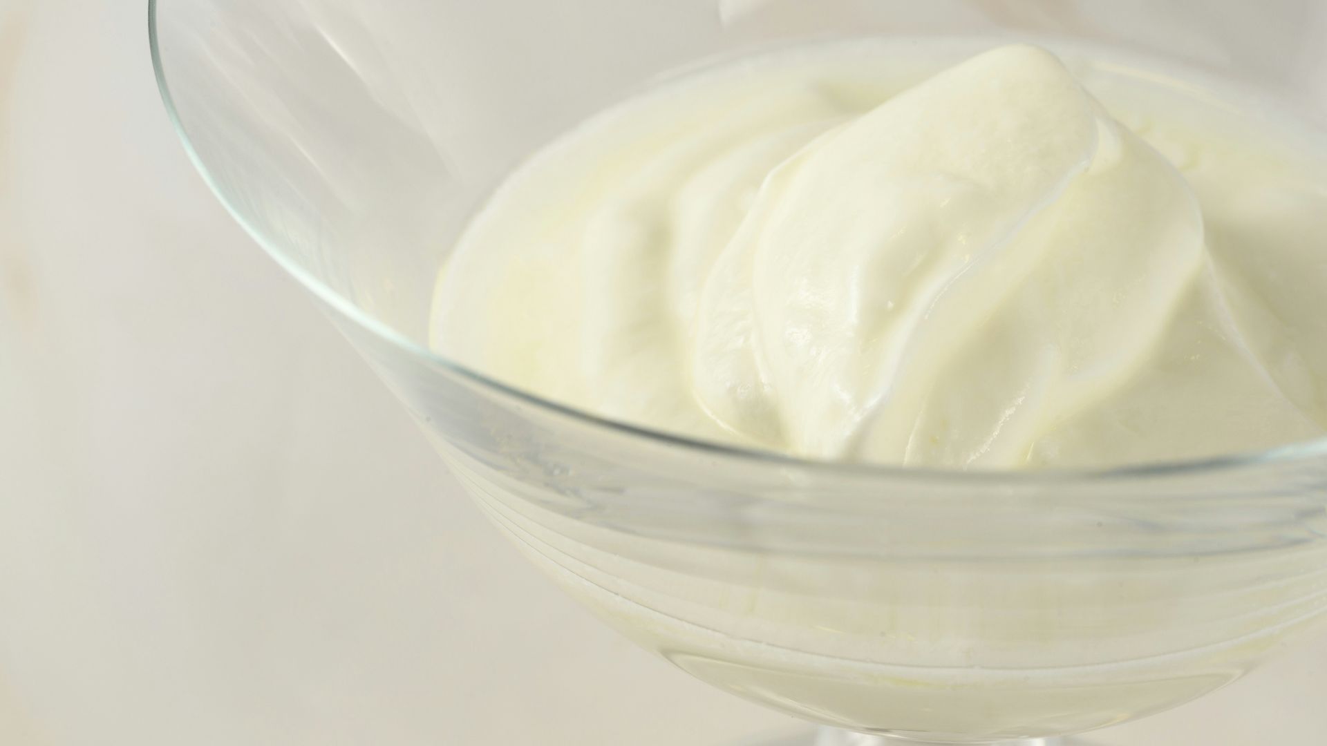 a glass bowl filled with cream on top of a table