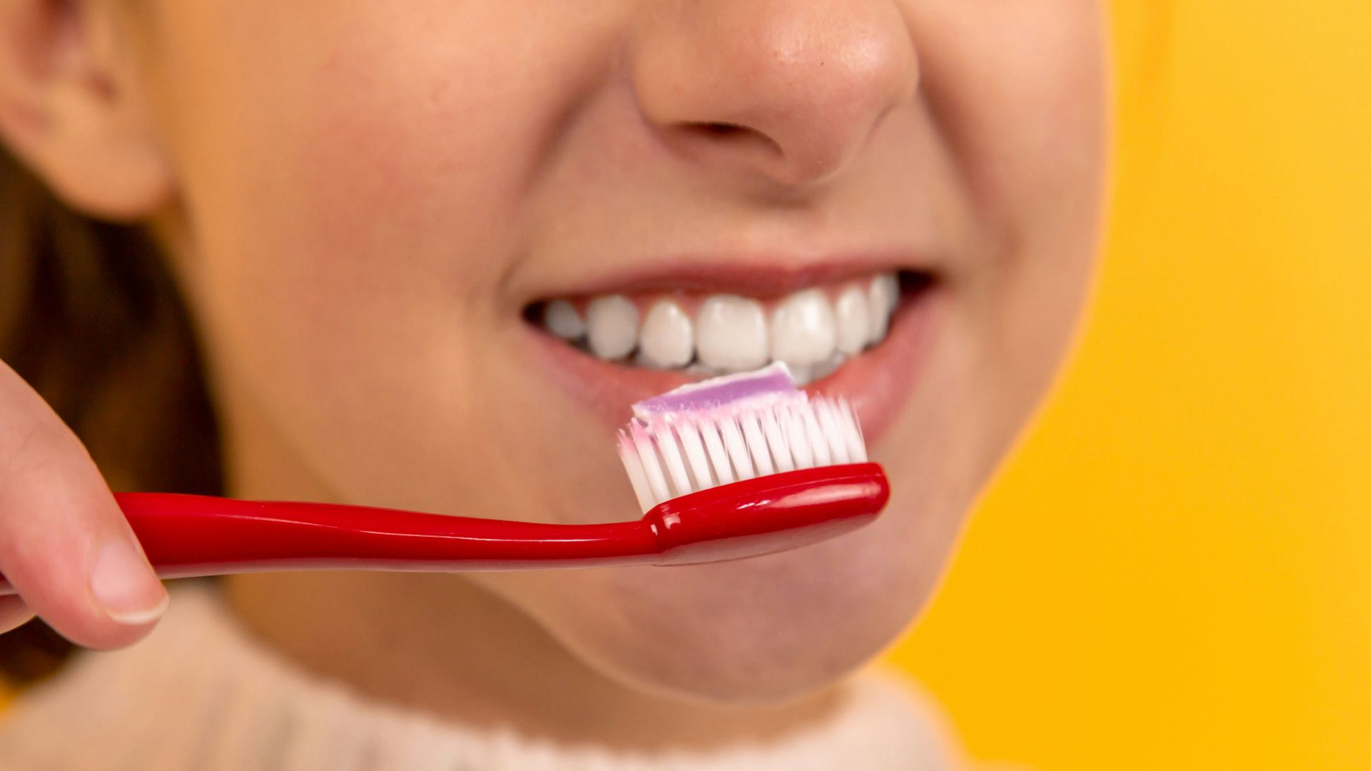 girl with red and white toothbrush in mouth