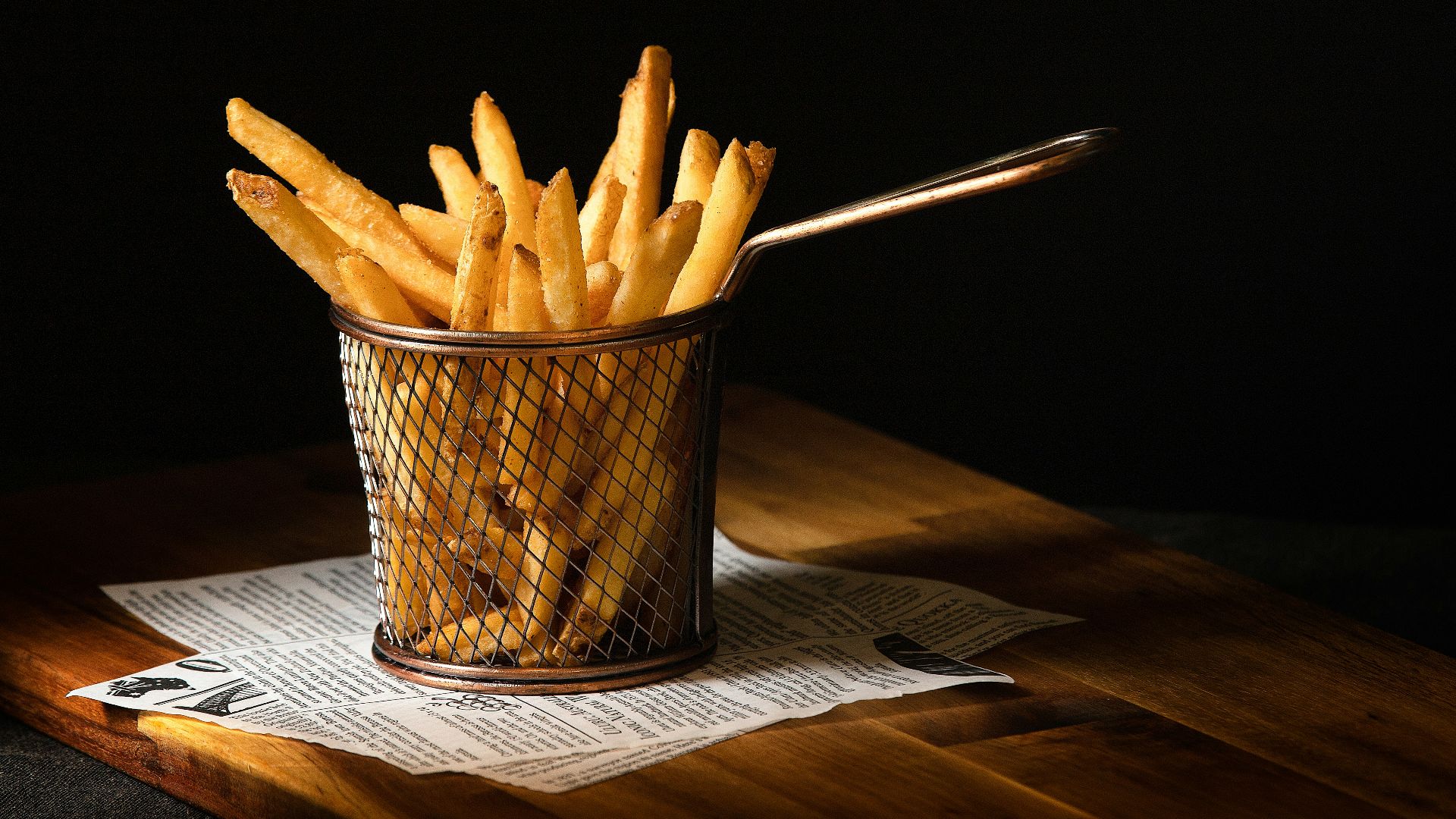 a basket of french fries sitting on top of a wooden table
