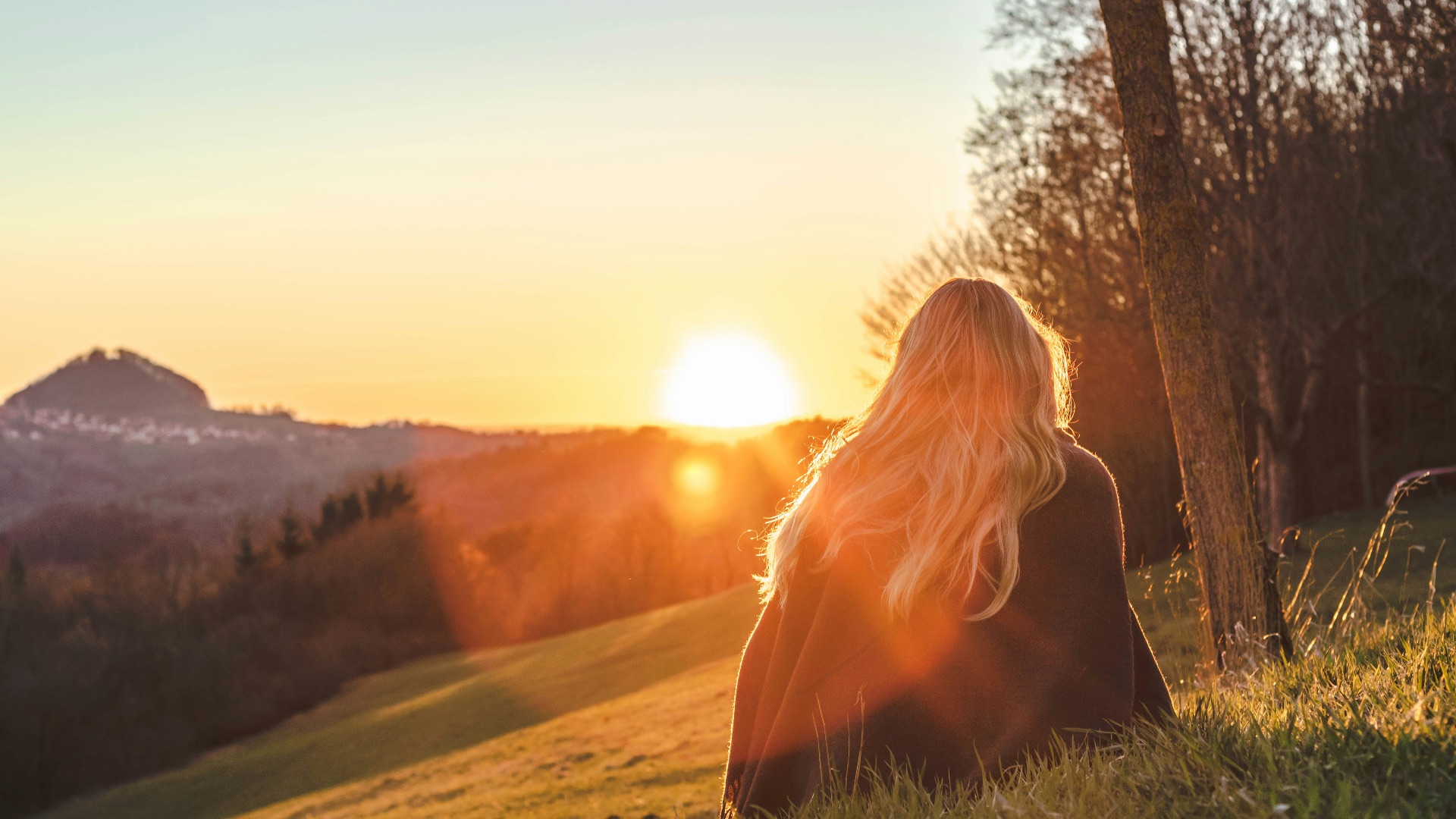 woman sitting on green grass looking at the sun