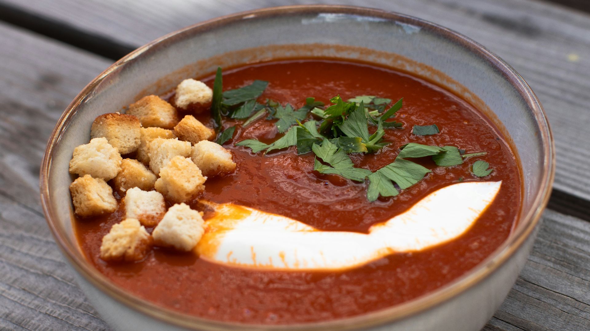 a bowl of tomato soup with croutons and parsley