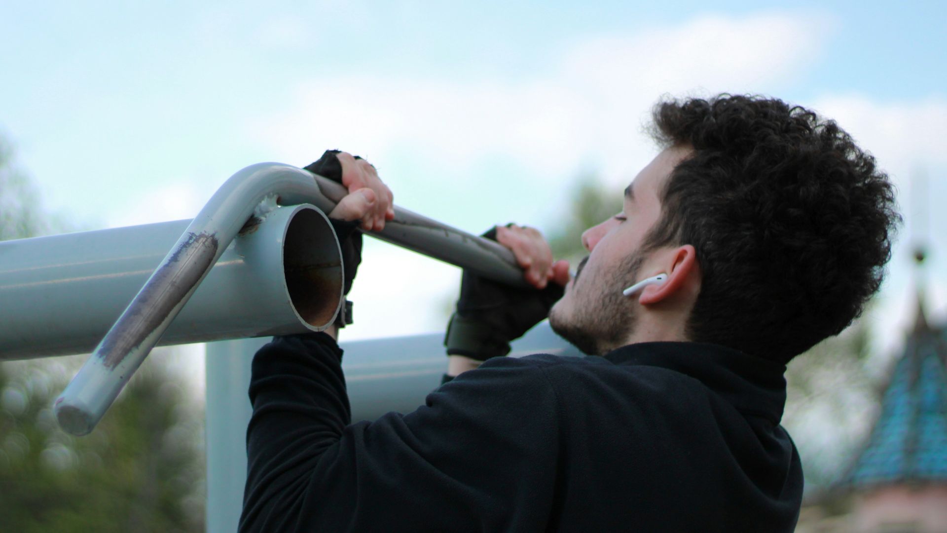 a man in a black jacket holding onto a metal pole