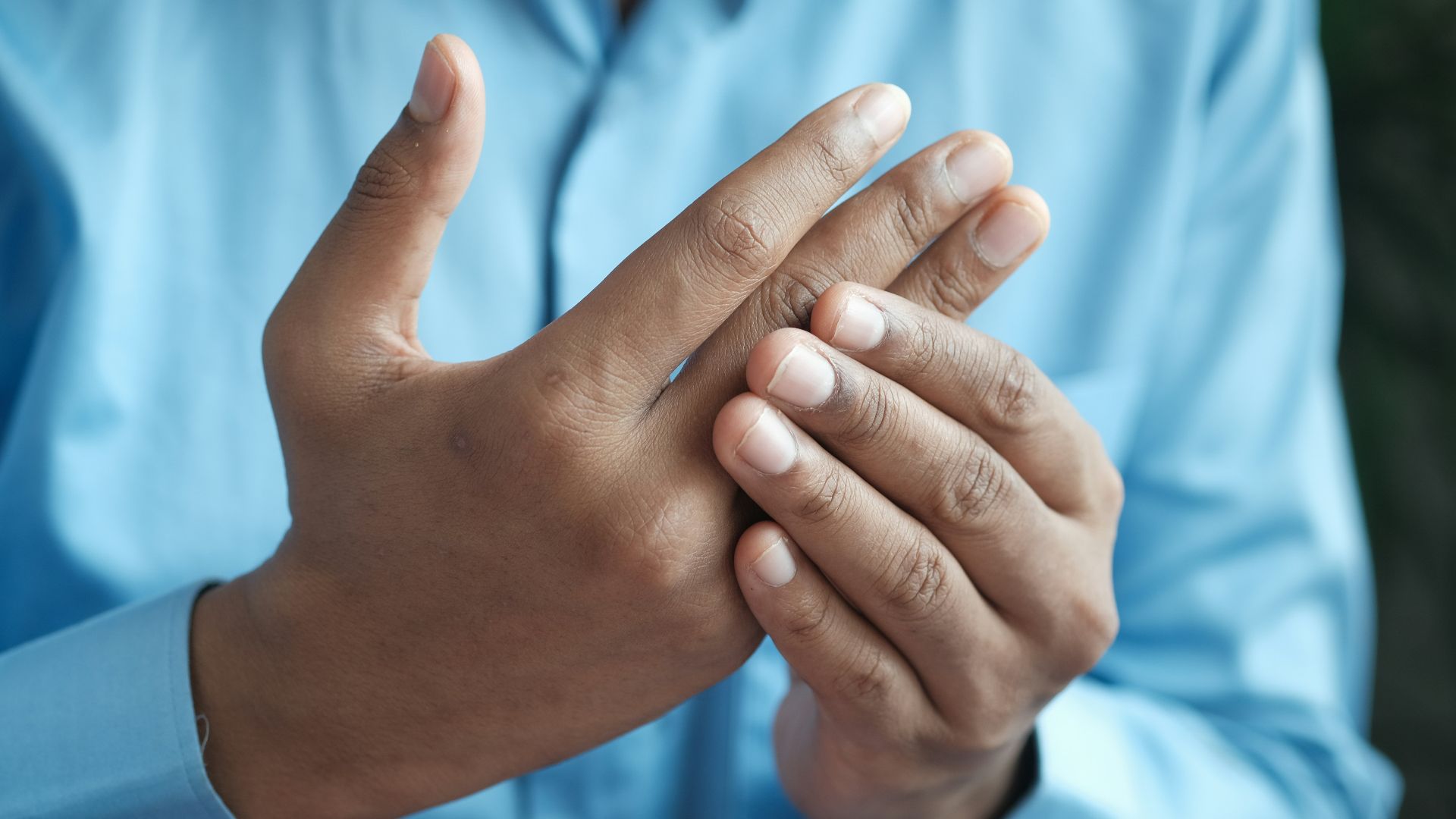 person in blue shirt showing left hand