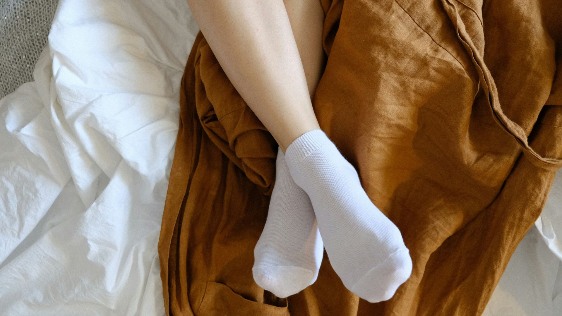 person wearing white socks lying on bed