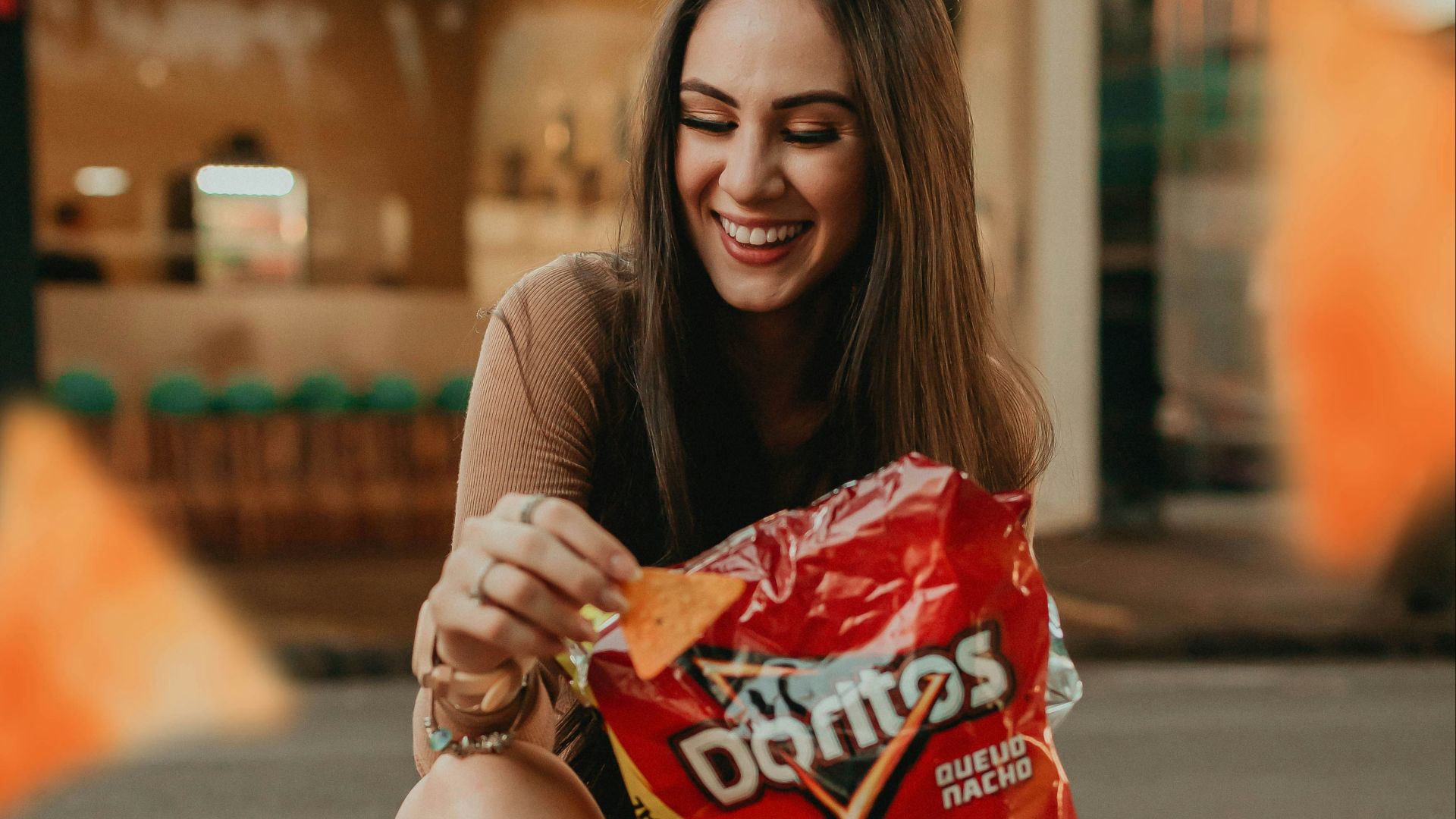 woman in black shirt sitting on the street holding red plastic pack