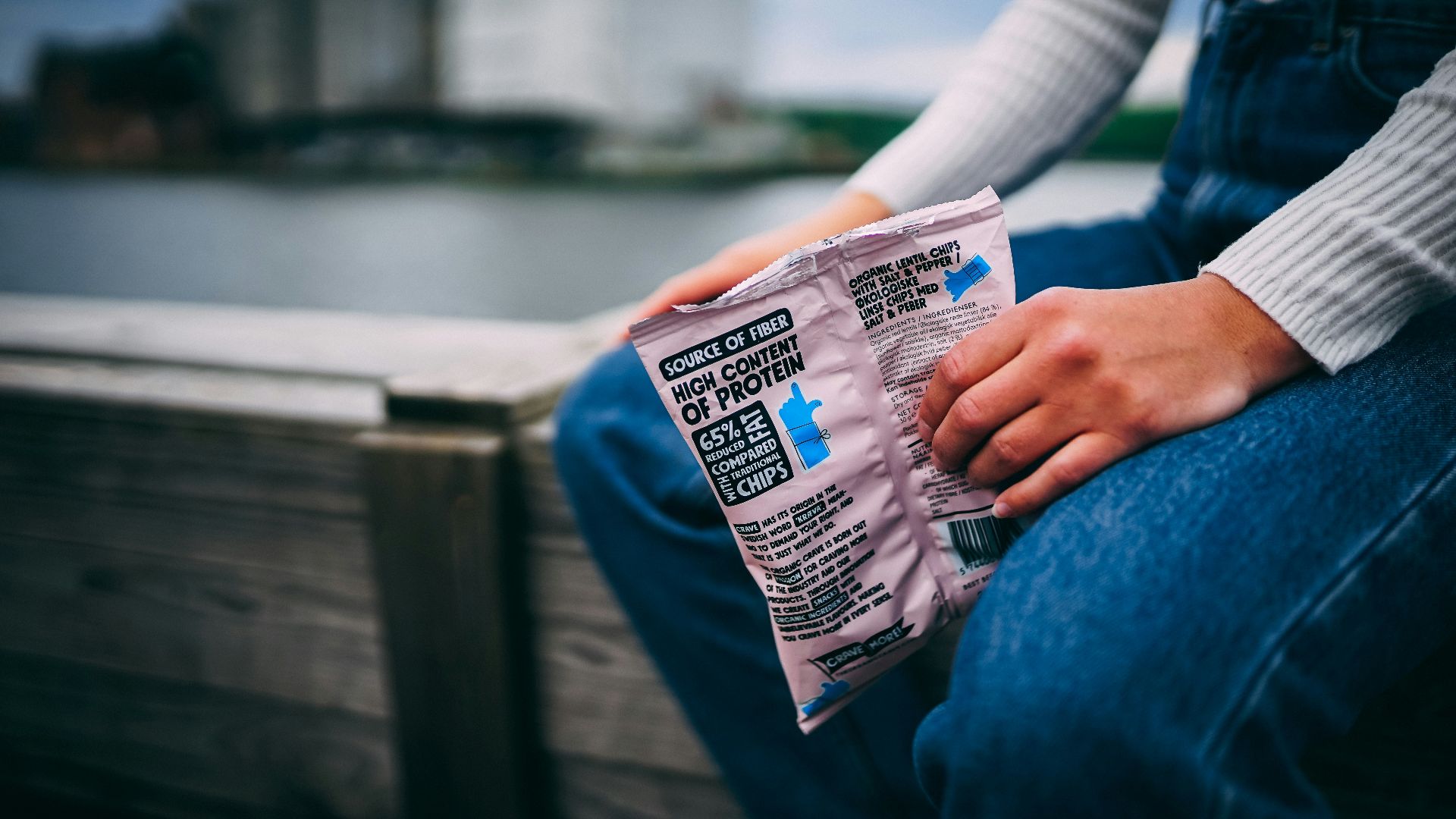 person holding white and blue plastic pack showing nutrition facts label