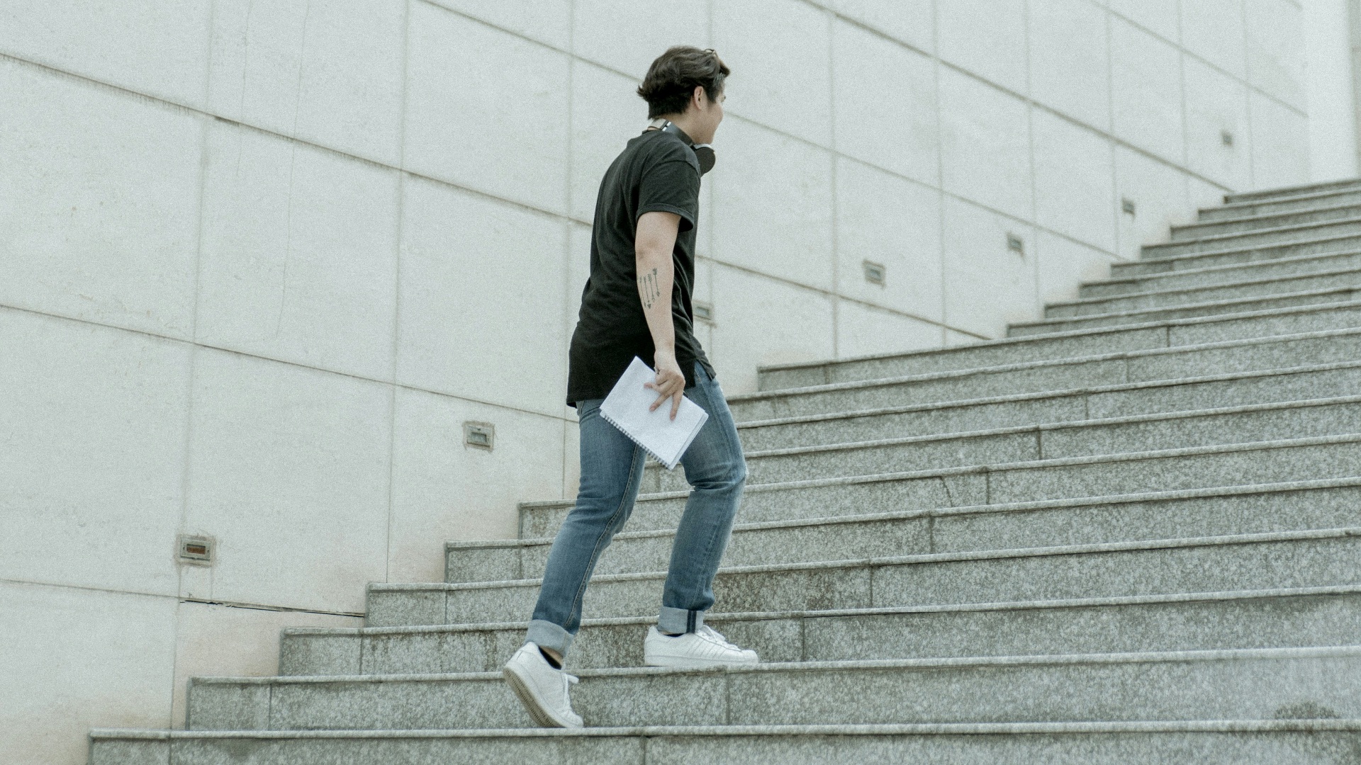 man holding white blanket paper walking on gray stair