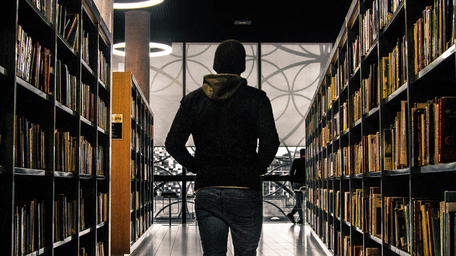 man walking between bookshelf