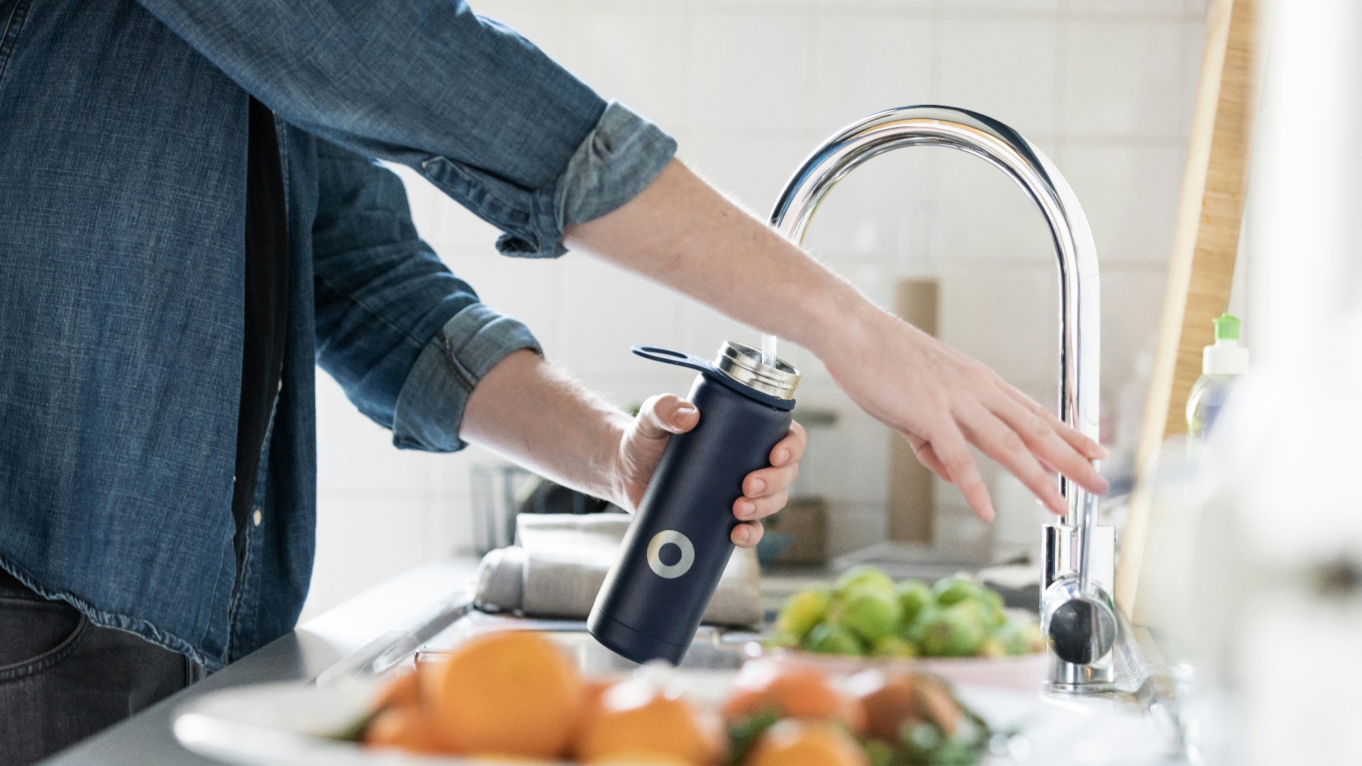 person in blue denim jacket holding stainless steel bottle
