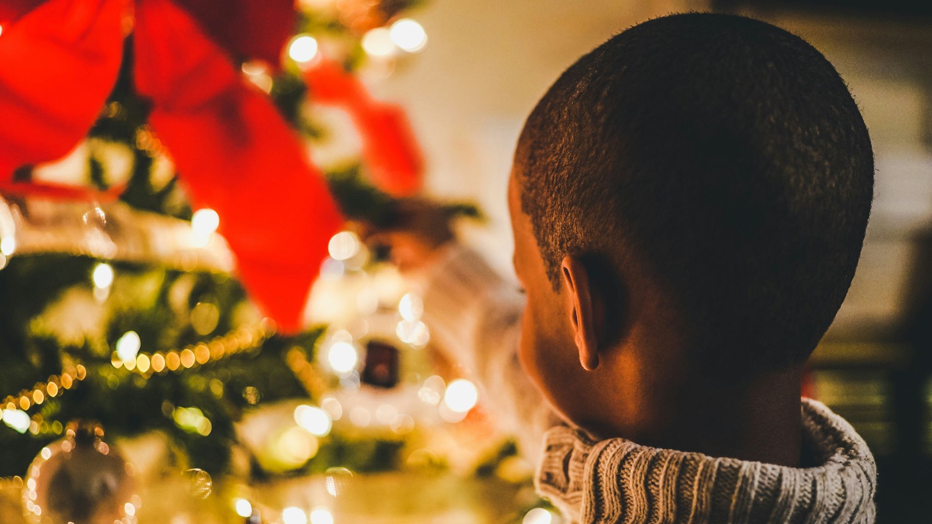 selective focus photography of boy near lit Christmas tree