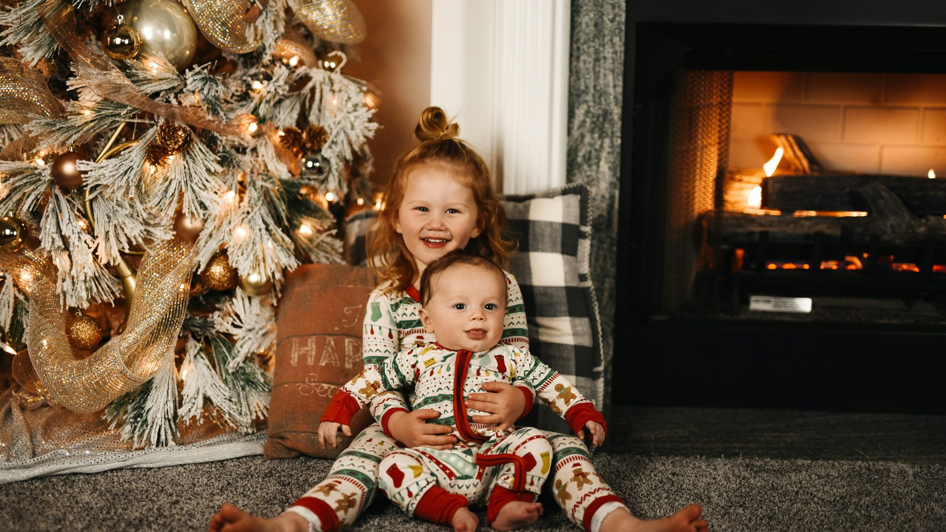 girl in red and white plaid pants sitting on floor beside brown and white floral sofa