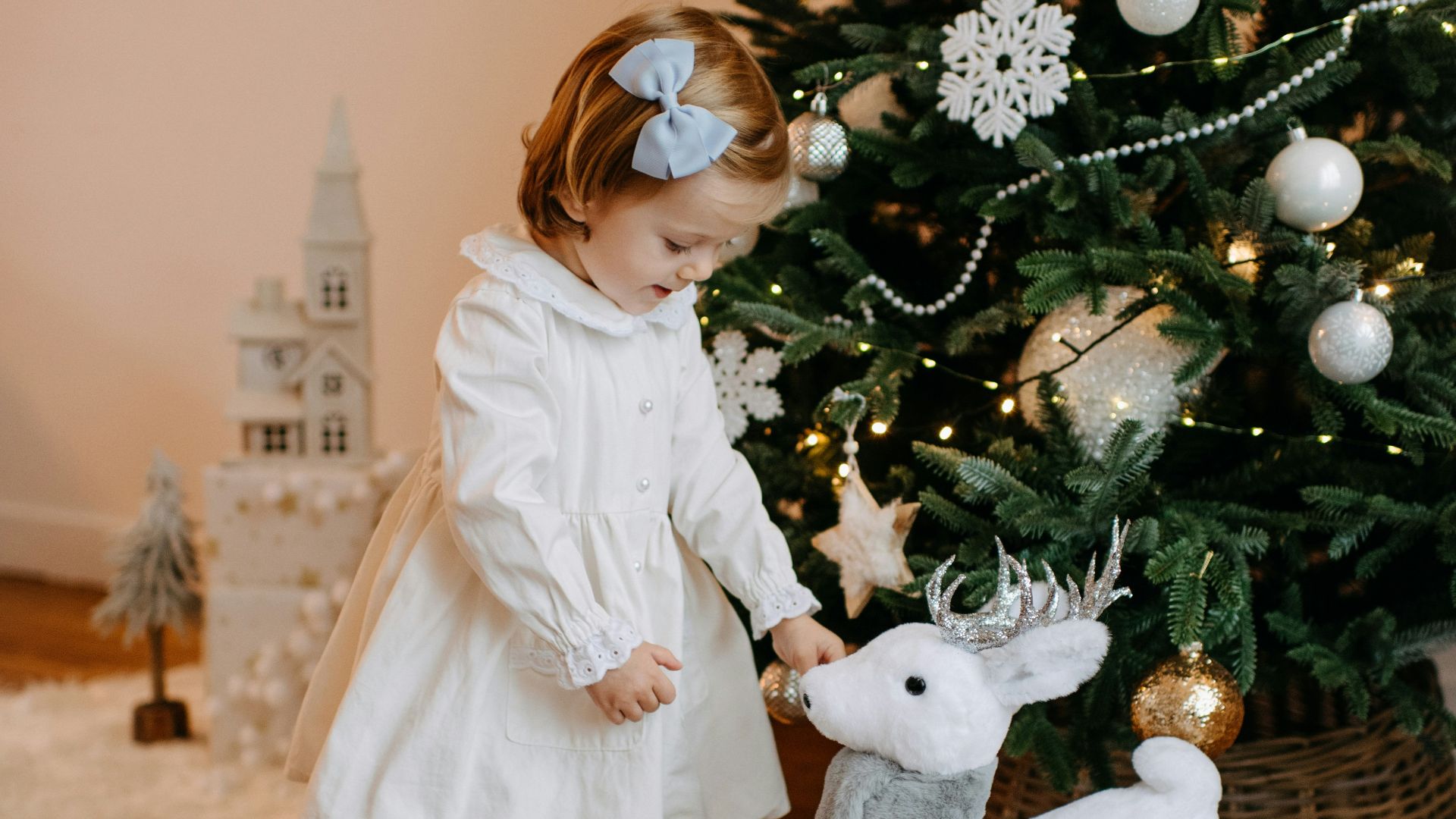a little girl standing next to a christmas tree