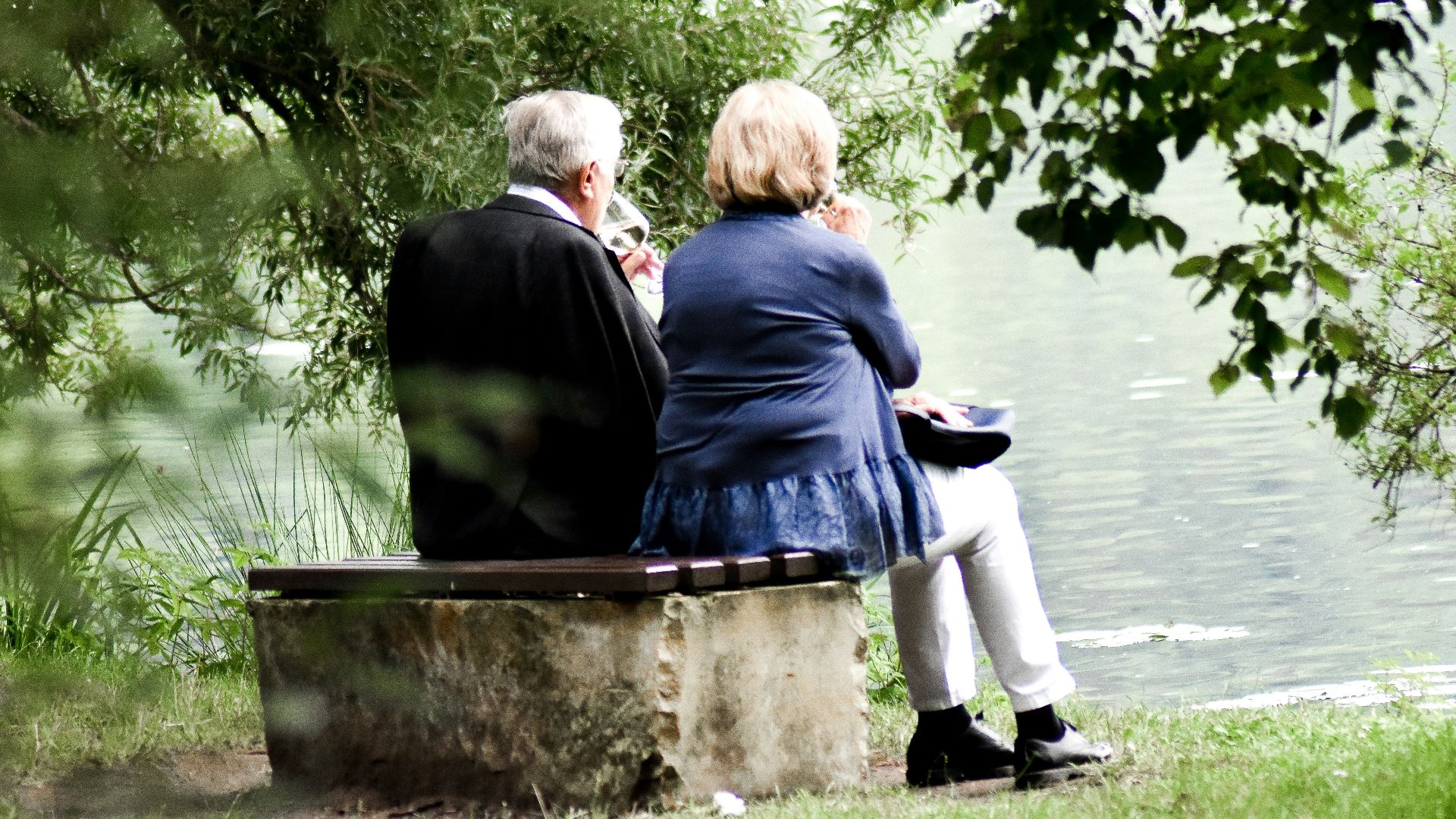 two people sitting on pavement facing on body of water