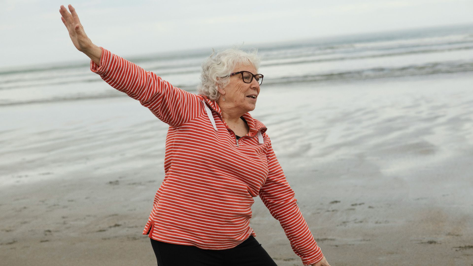 Woman practices tai chi on the beach.