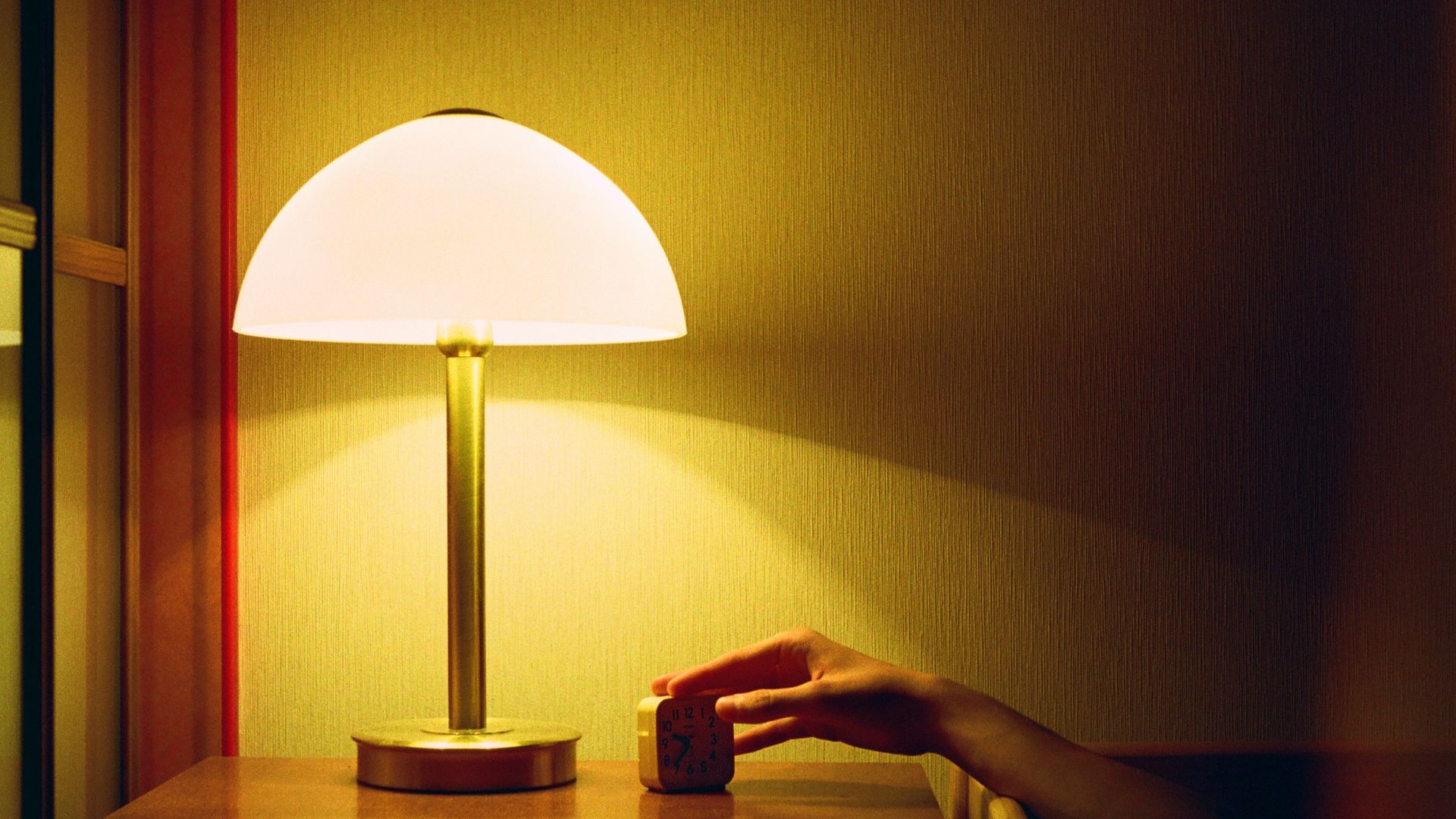 a person's hand on a table next to a lamp