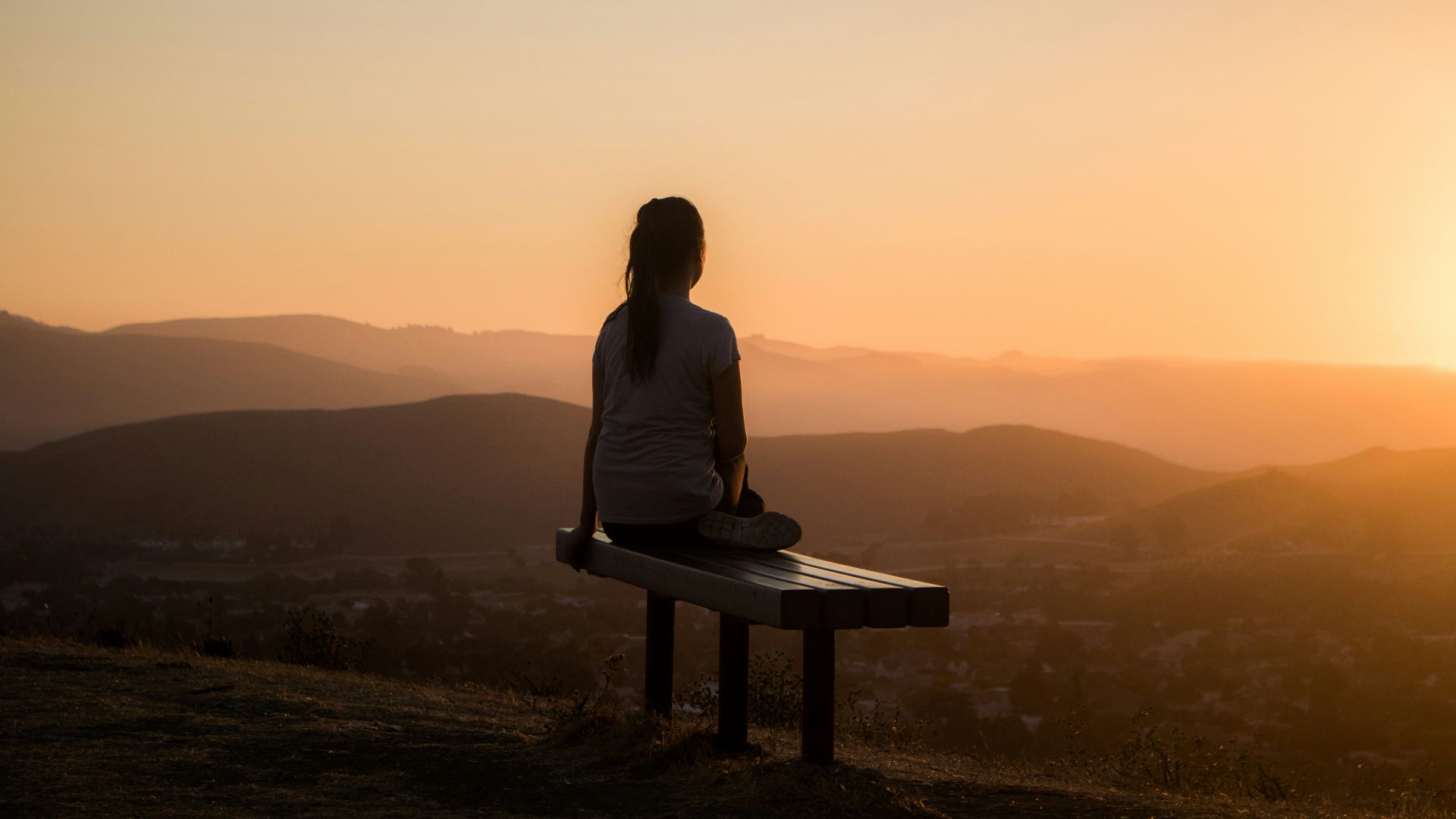 woman sitting on bench over viewing mountain
