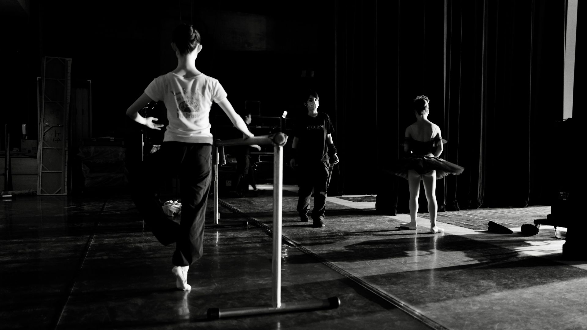 Ballet dancers practicing at a barre in a studio.