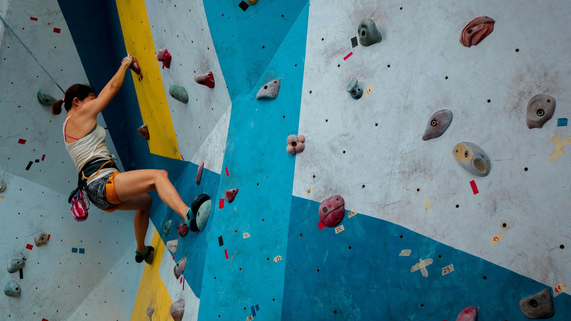 person in white tank top rock climbing
