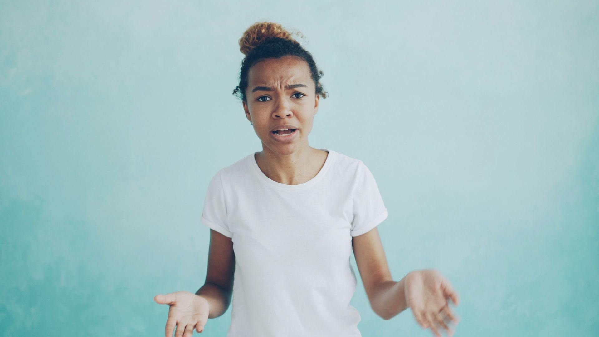 Young woman with confused expression against blue background