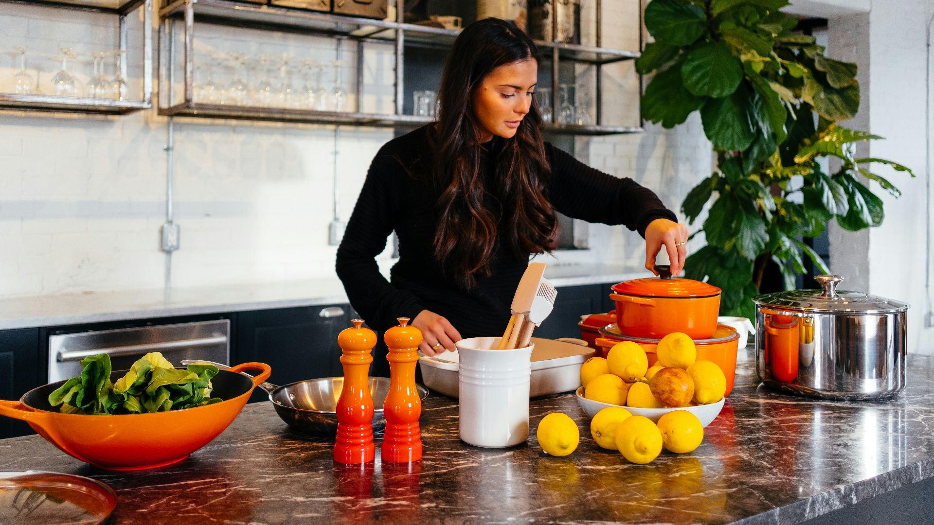 woman standing in front of fruits holding pot's lid