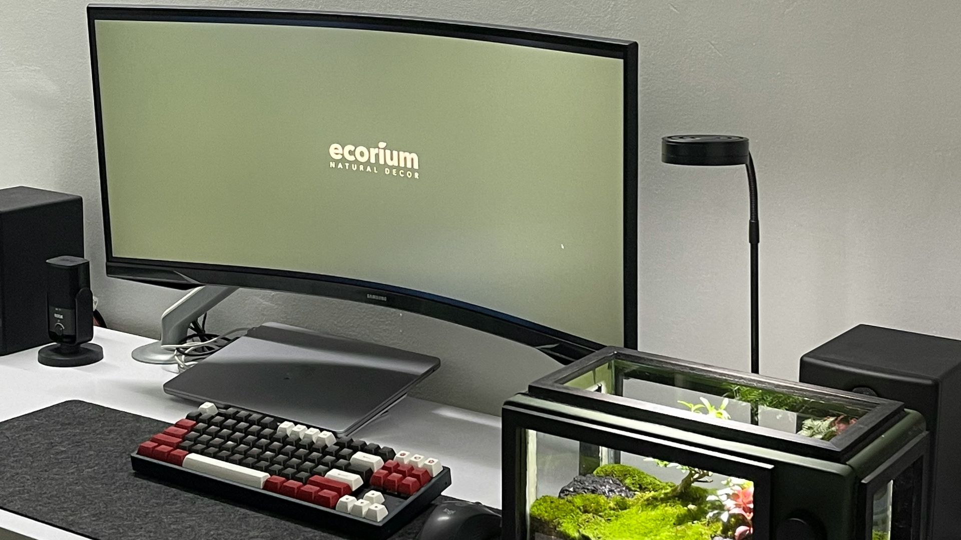 a desk with a monitor, keyboard and a remote control