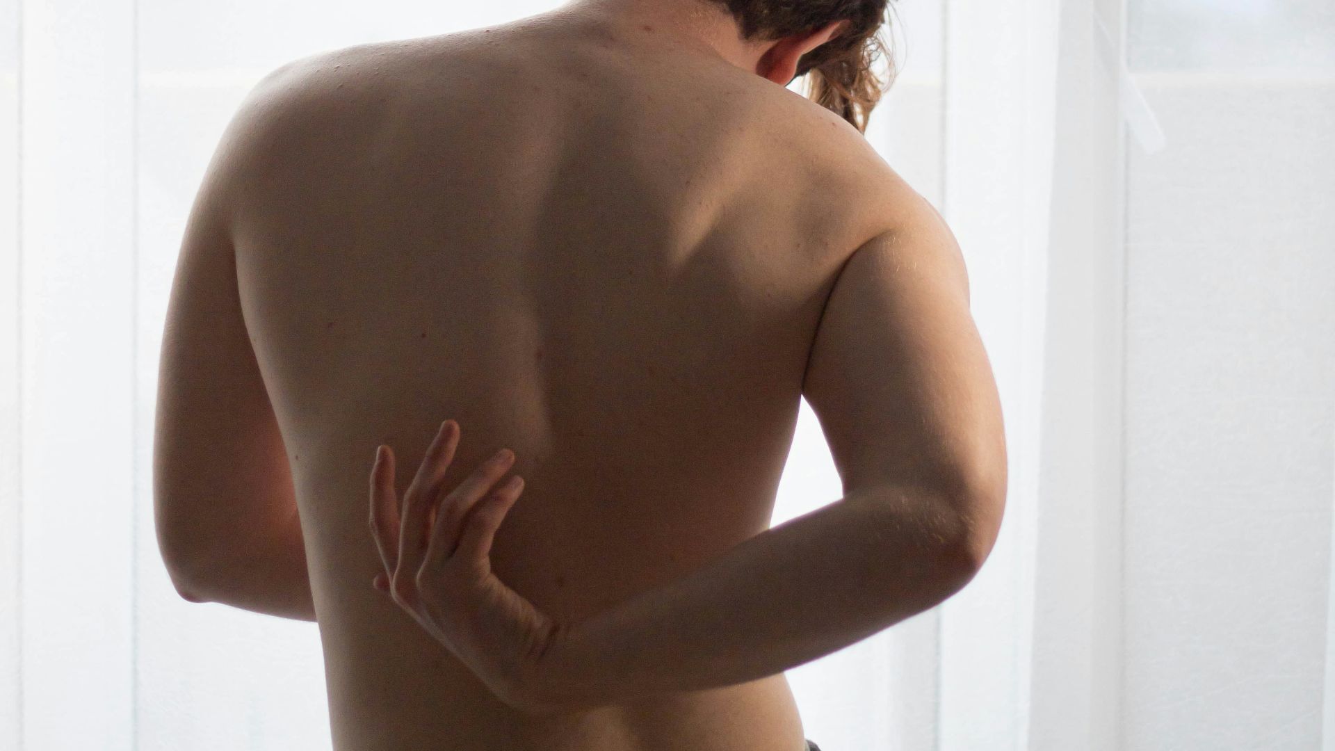 topless woman standing near window