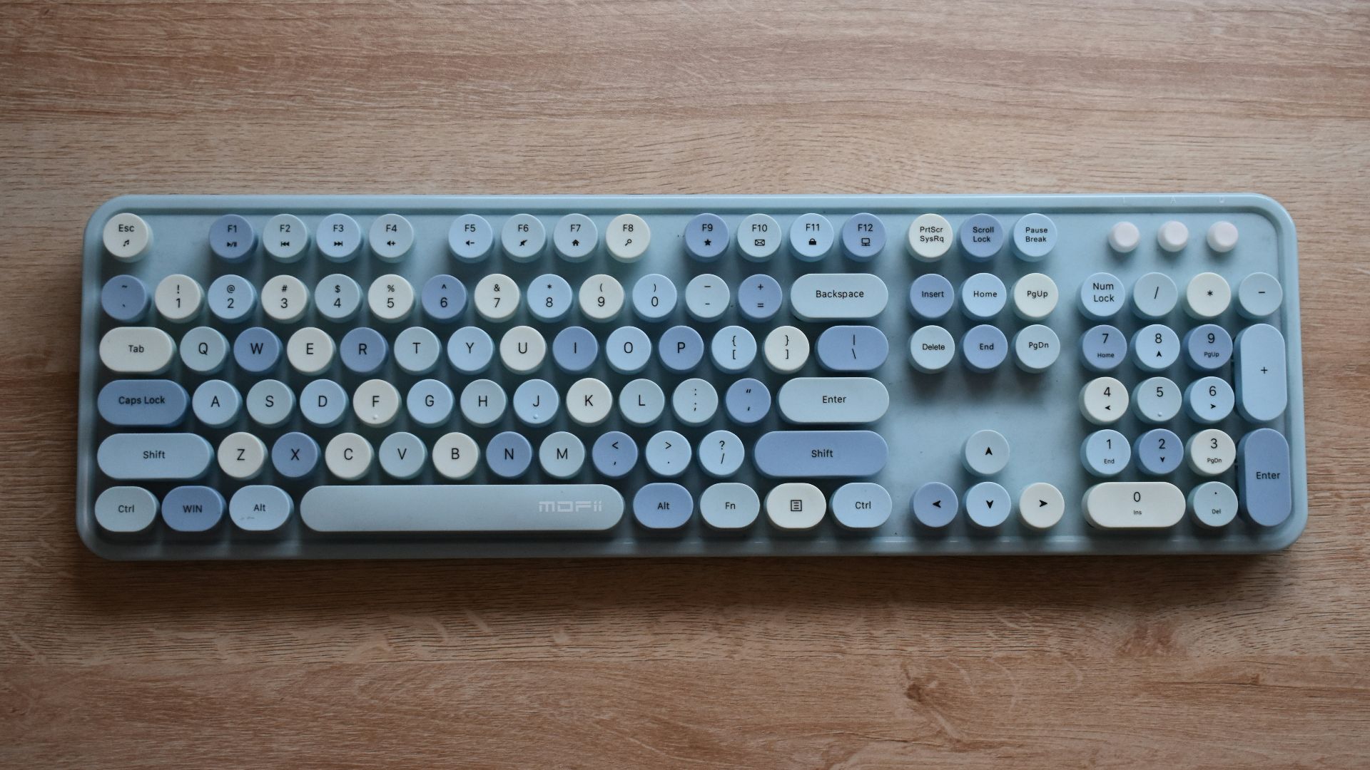 A computer keyboard sitting on top of a wooden table