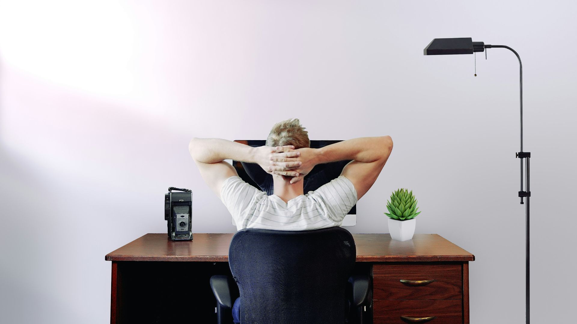 man holding his head while sitting on chair near computer desk