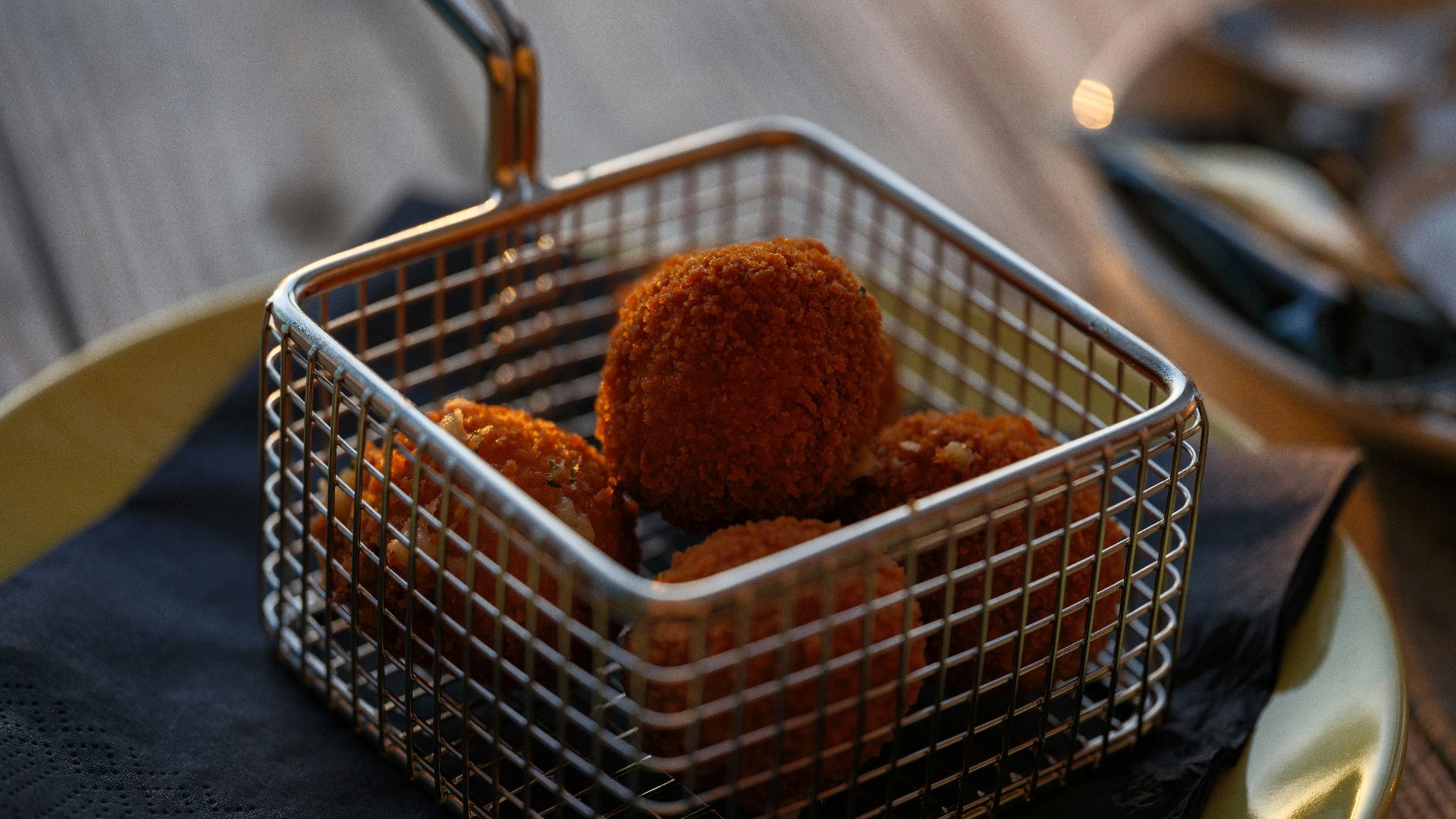 A metal basket filled with food on top of a wooden table
