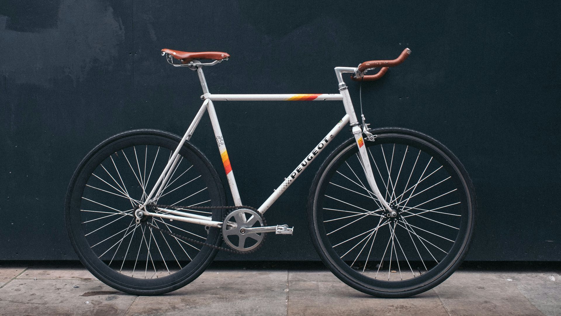 gray fixie bike leaning on black wall