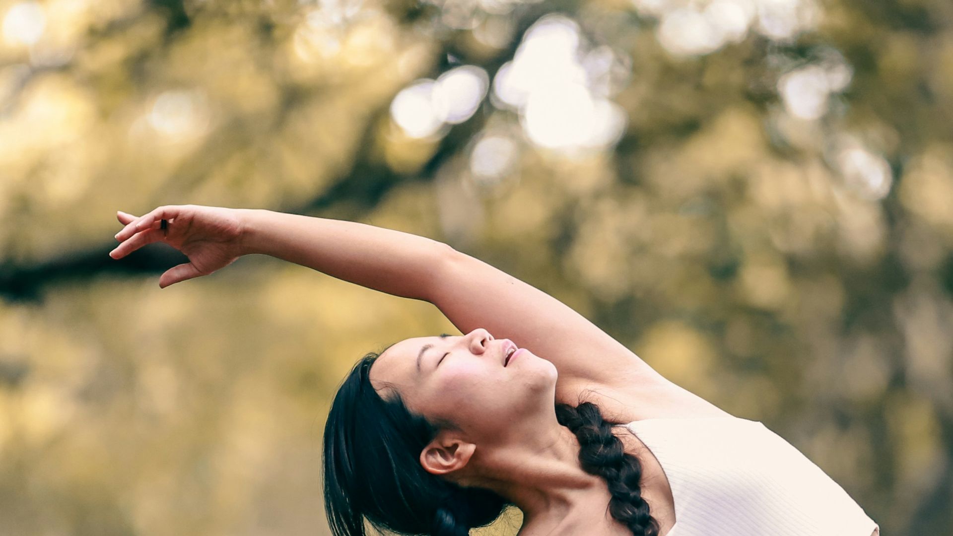 woman in white tank top and black leggings doing yoga during daytime