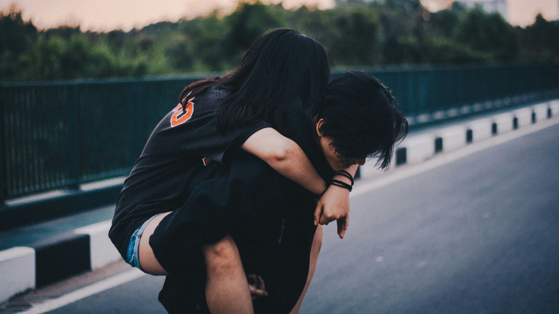 woman piggyback on man standing on gray concrete road during daytime