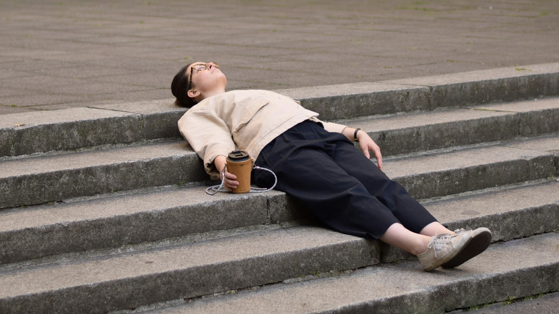man in brown hoodie and black pants sitting on gray concrete stairs