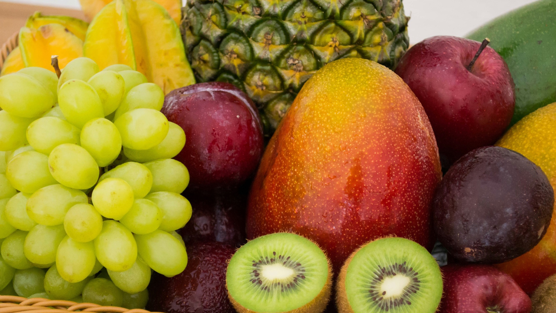 red apple fruit beside green apple and yellow fruit on brown woven basket