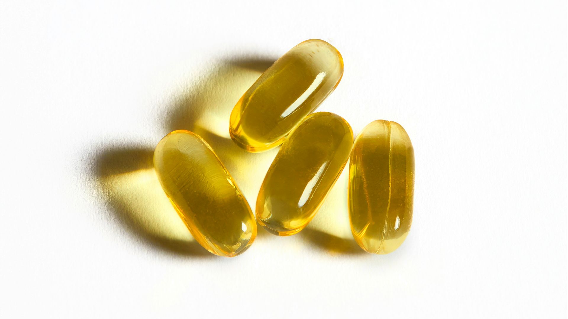 Four yellow capsules sit on a white surface.
